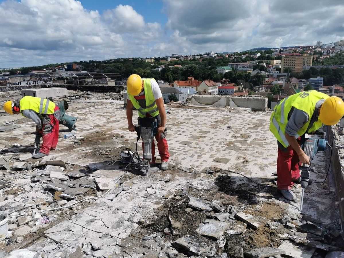 Three workers with electric breakers removing the layers of a flat roof